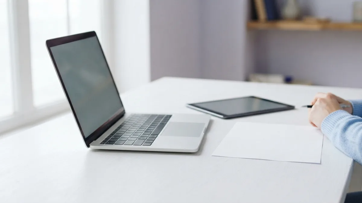 Reviewing a document on a laptop Laptop and blank tablet beside paper in a bright workspace