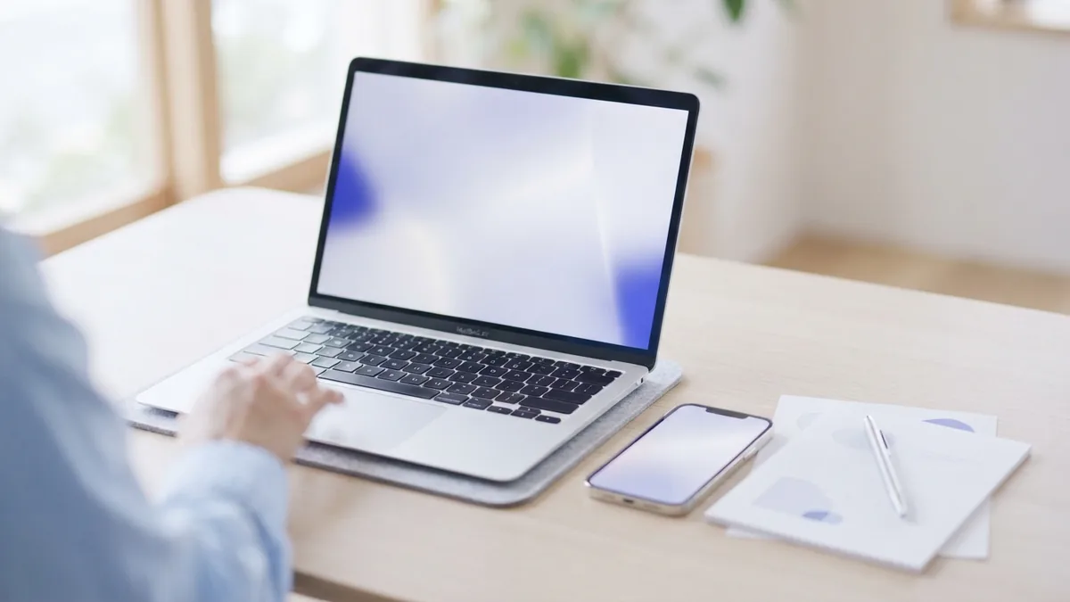 Laptop and phone beside documents on a bright desk for online PDF page work