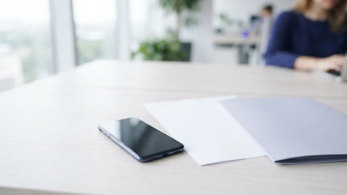 Mobile setup for PDF image tasks Phone beside blank paper and a folder for saving PDF images on mobile