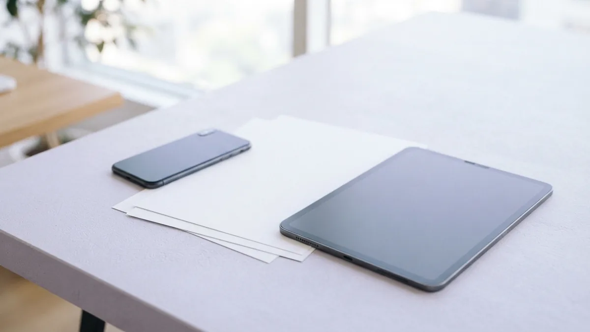 Mobile devices beside scan-ready pages Phone and tablet beside blank sheets for scanning a document on the go